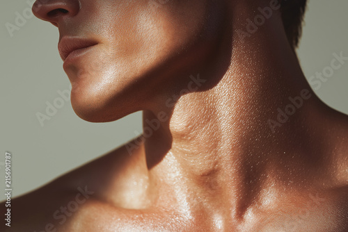 Glossy male neck and jawline with dewy skin catching light, close up showing texture and sheen conveying healthy skincare and subtle emotion