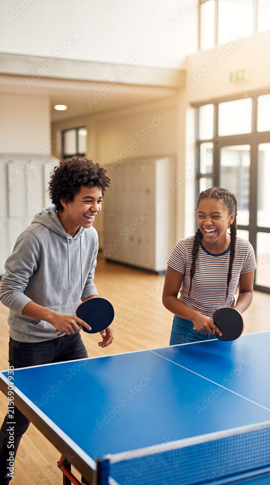 Fototapeta premium Teenage friends playing table tennis in school hallway. Sports, recreation, youth activity, education.