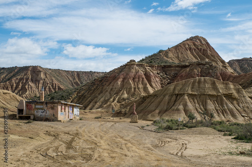 An old house with graffiti in front of some hills in the semi-desert Bardenas Reales, Spain
