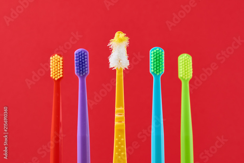 Foto Old worn toothbrush facing new colorful toothbrushes, representing dental care r