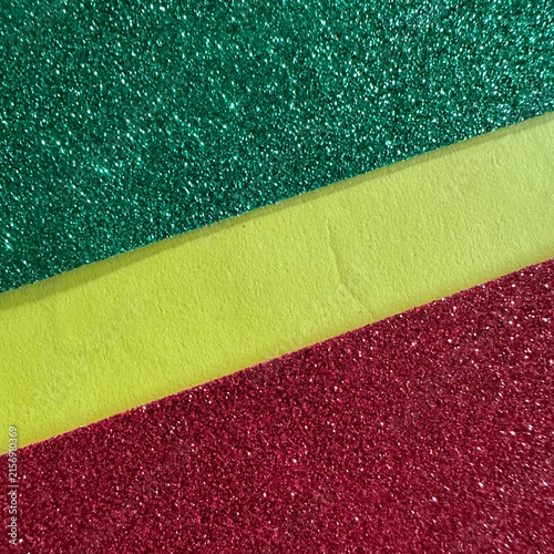 Diagonal stripes of green glitter, yellow paper, and red glitter