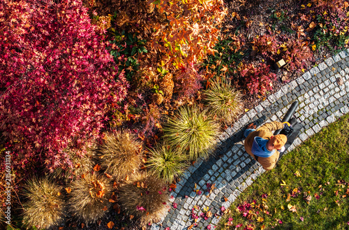 Gardener using a leaf blower in a colorful autumn garden