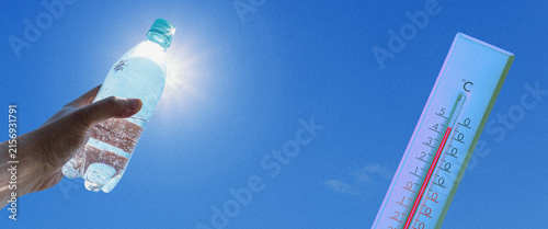 Fotografie Hand holding cold water bottle next to thermometer during extreme summer heatwav
