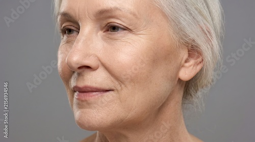 Three quarter profile view portrait of elegant senior woman with crow's feet and clear skin