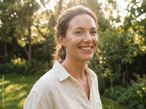 Radiant middle aged woman smiling warmly while enjoying a peaceful afternoon in a lush green sunlit garden with soft lighting