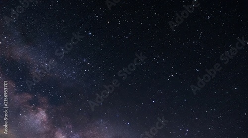 A breathtaking view of the night sky filled with countless stars and the Milky Way galaxy. Dark clouds streak across the heavens, creating a dramatic and ethereal backdrop.