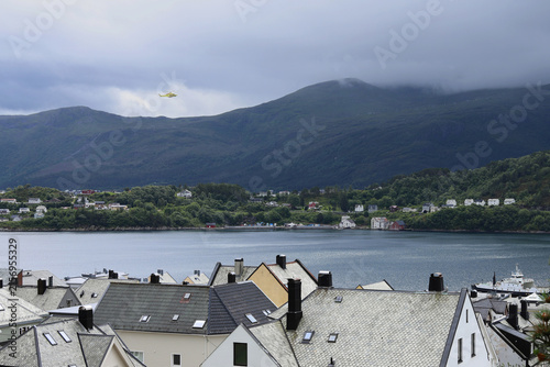 Alesund city roofs, ocean bay and surrounding mountains, Norway. Scandinavian cityscape with traditional coastal houses.