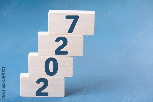 2027 Happy New Year. Wooden cube block steps growth 2027 on blue. Concept 2027 New Year background. Business, resolutions, goals, inspiration, success, ideas