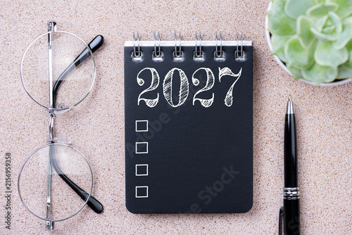 New year goals 2027. 2027 resolutions list with notebook, coffee cup, plant on table. Resolutions, plan, goals, action, checklist, idea concept. New Year 2027 resolutions, copy space