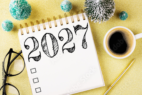 New year resolutions 2027 on desk. 2027 resolutions list with notebook, coffee cup, decorations on table. Goals, resolutions, plan, action concept. New Year 2027 template. Copy space