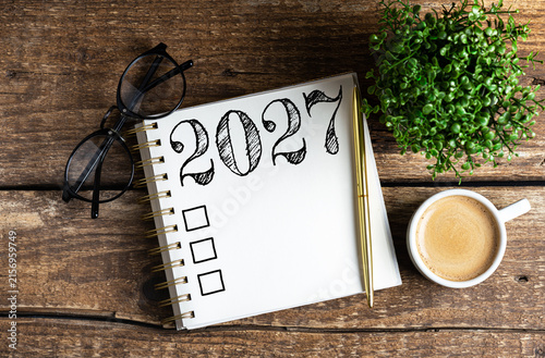 New year resolutions 2027 on desk. 2027 goals list with notebook, coffee cup, plant on wooden table. Resolutions, plan, goals, action, checklist, idea concept. New Year 2027 resolutions, copy space