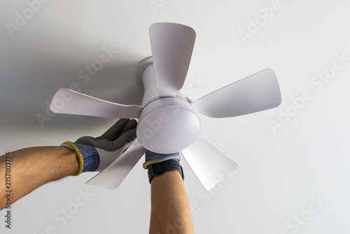 Installing a ceiling fan to improve air circulation and home comfort during hot summer weather, showing hands-on electrical and home improvement work.