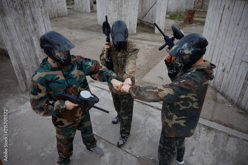 An armed group of several soldiers make a commanding gesture as they prepare on training field