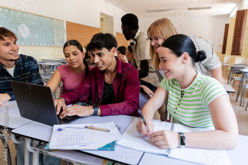 Diverse students collaborating on laptop in classroom for education