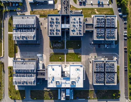 Vertical top-down aerial view of a large modern data centre campus, featuring symmetrical buildings, precise geometry, access roads and organized infrastructure.