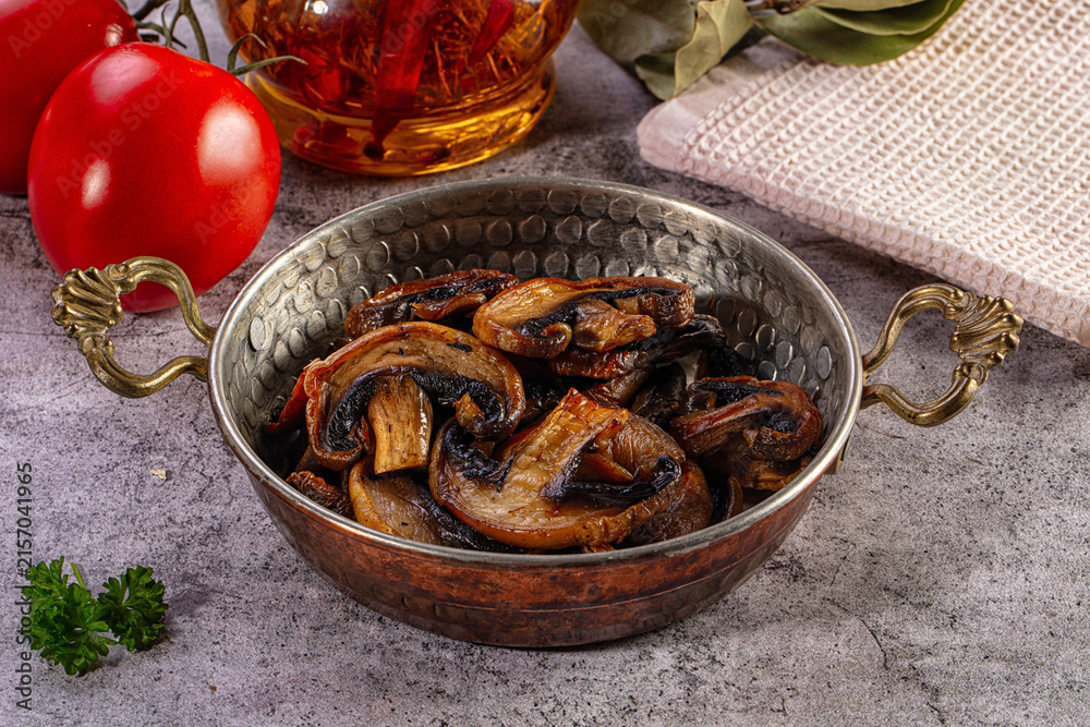 Fototapeta premium Sauteed mushrooms in a traditional copper pan with fresh tomatoes and herbs