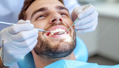 The dentist is examining his male patient's teeth.