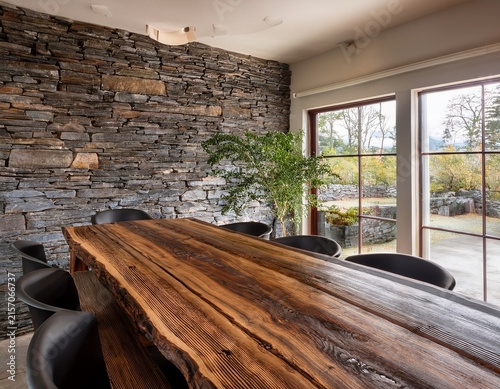 rustic dining area features a substantial live edge wooden table against a fieldstone wall