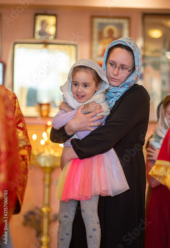 Bild auf Leinwand Mother brings her daughter to Communion in church, girl smiles happily