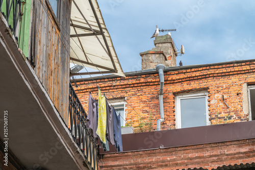 Bild auf Leinwand Laundry Hanging in a Historic Brick Courtyard with Rooftops and Birds Under Blue Sky