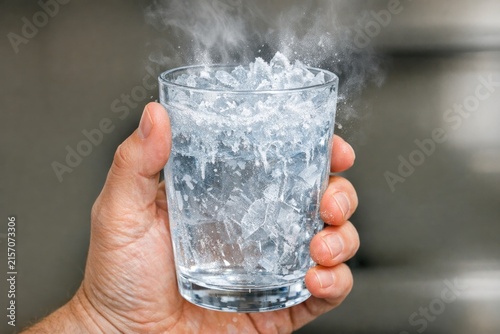 A person holds a glass of water with ice cubes, ready to quench their thirst