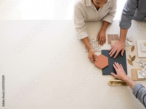 Top view of interior designers selecting tiles, wood, and stone material samples on a table with copy space