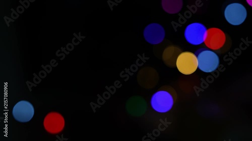 Out of focus colorful bokeh lights on a black background with glowing circles