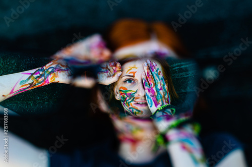 Artistic woman portrait with colorful paint on face and hands