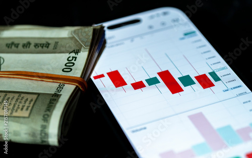 Indian 500 rupees banknotes placed against a stock market chart, symbolising currency, investment, finance and economic growth