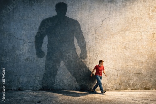 A person walking by a wall with a shadow of another person, good for use in scenes about mystery or intrigue