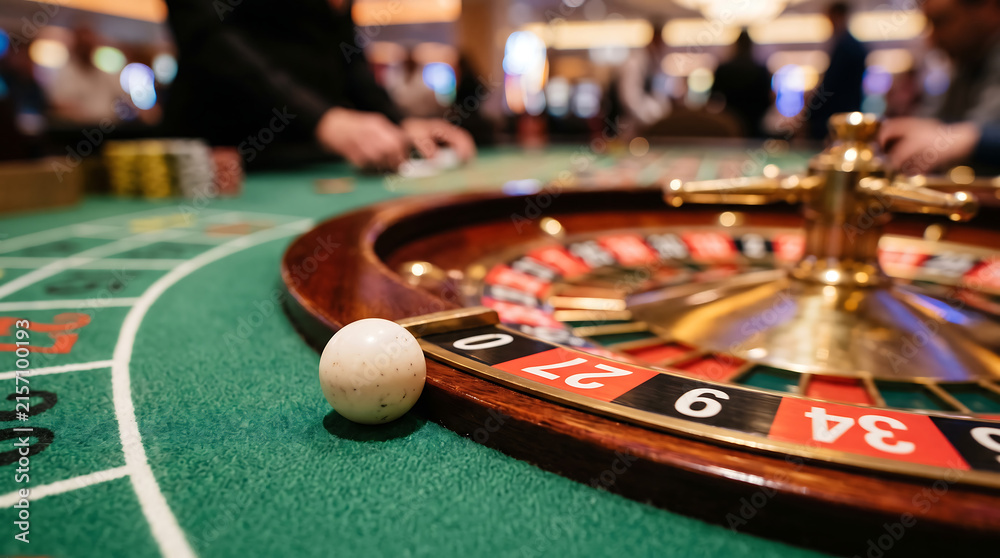 Obraz premium Luxury casino roulette wheel on a professional gaming table, red black and green numbered pockets, polished wooden and metal details, casino chips around the wheel