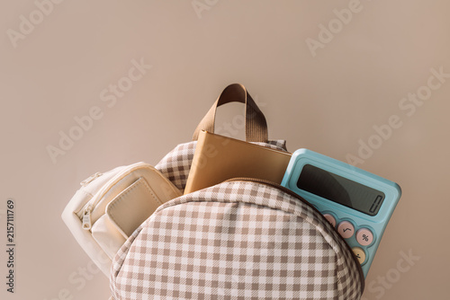 School backpack with notebook and blue calculator, stylish back to school background.