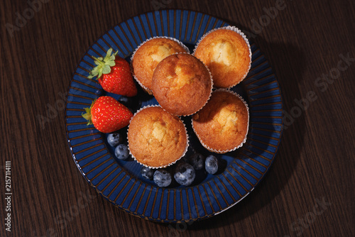 Top view of muffins with strawberries and blueberries on a blue plate