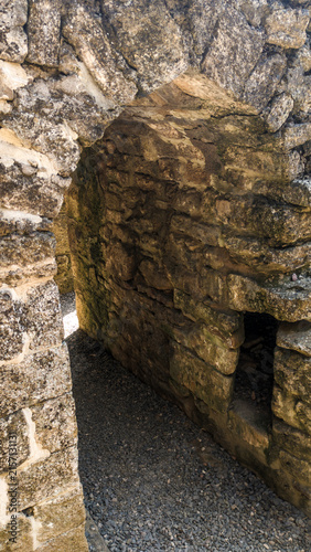 Fotografie A stone wall with a small window, suitable for use as a background or to illustr
