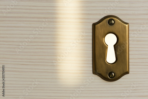 Brass keyhole with light passing through hope and mystery concept