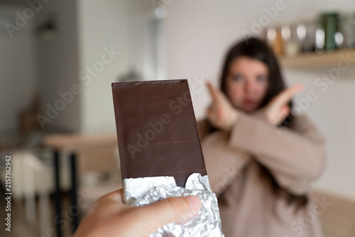 Photography Chocolate in foil and a woman with crosswise hands refuses to eat