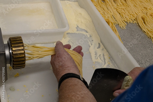 Chef hands holding fresh pasta at commercial pasta maker in restaurant kitchen