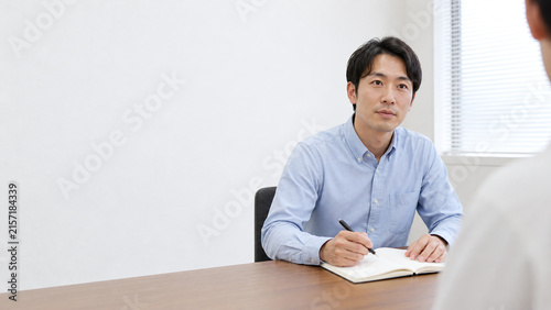 Naklejka ノートを取りながら話を聞く日本人男性 面談と余白のある背景