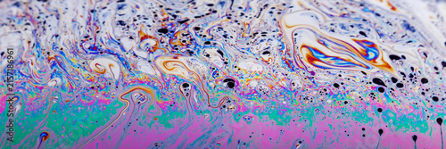 Close crop of interference colors forming kaleidoscopic pockets and lace‑like membranes in a vivid, textured panorama.
