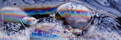 Close-up of curved thin‑film membranes showing glossy teardrop patterns and subtle gradient transitions against a black backdrop.