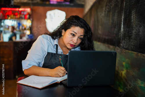Latin woman entrepreneur planning small business in cafe