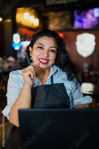 Hispanic woman entrepreneur managing small business with laptop