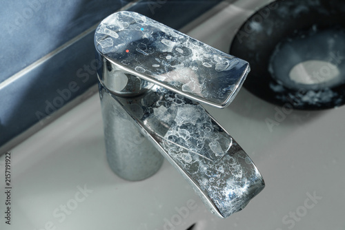 Close view of a bathroom faucet heavily affected by limescale deposits from hard water