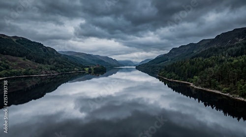 Loch Ness Scotland calm pewter water with brooding pine-forested hills and cloud, Professional Editorial Nature Photograph.