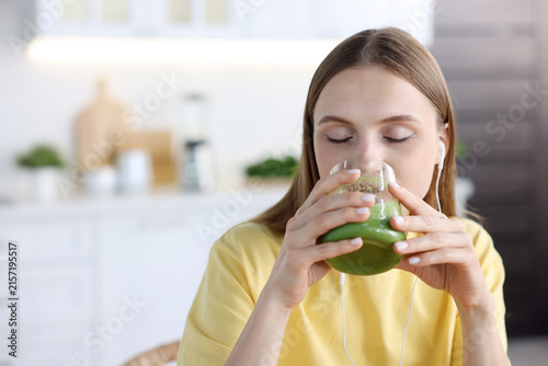 Obraz na plátně Woman drinking green smoothie from glass at home, space for text