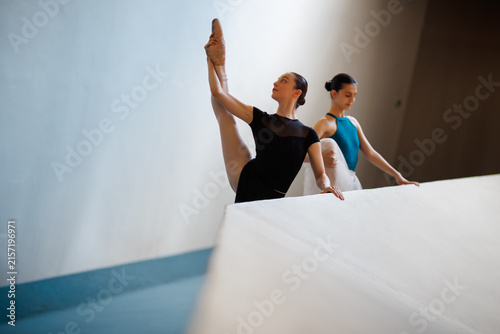 Obraz na płótnie Two ballet dancers stretching at a barre during rehearsal, ballerinas practicing