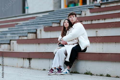 Canvas Print Young couple sitting closely on outdoor steps, expressing affection and bonding