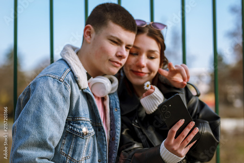 Quadro su tela Young couple taking a selfie in a park during bright afternoon, enjoying casual