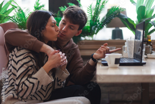 Fotografie A couple enjoying a cozy moment together while using a laptop in a modern cafe w