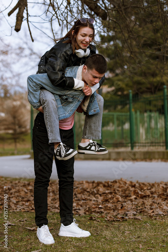 Quadro su tela Young couple enjoying a playful moment outdoors with one partner giving a piggyb